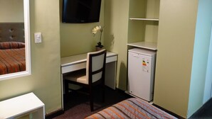 A small room with a bed, a desk, a chair, a television, and a refrigerator. - Hotel Posadas (Posadas)