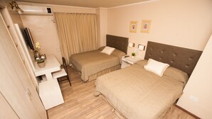 A hotel room with two beds, a desk, a chair, a TV, and a window with curtains. - Hotel Posadas (Posadas)