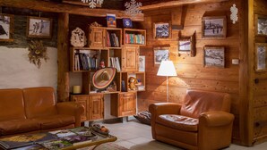 Una habitación acogedora con paredes de madera, un sofá de cuero, un mueble de madera lleno de libros y cuadros enmarcados.
