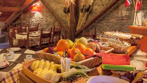 Un comedor con pared de piedra, vigas de madera y una variedad de frutas y verduras sobre la mesa.