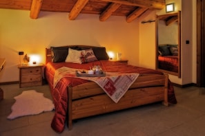 Un dormitorio acogedor con una cama de madera, mesitas de noche con lámparas, un espejo y una alfombra blanca y mullida.