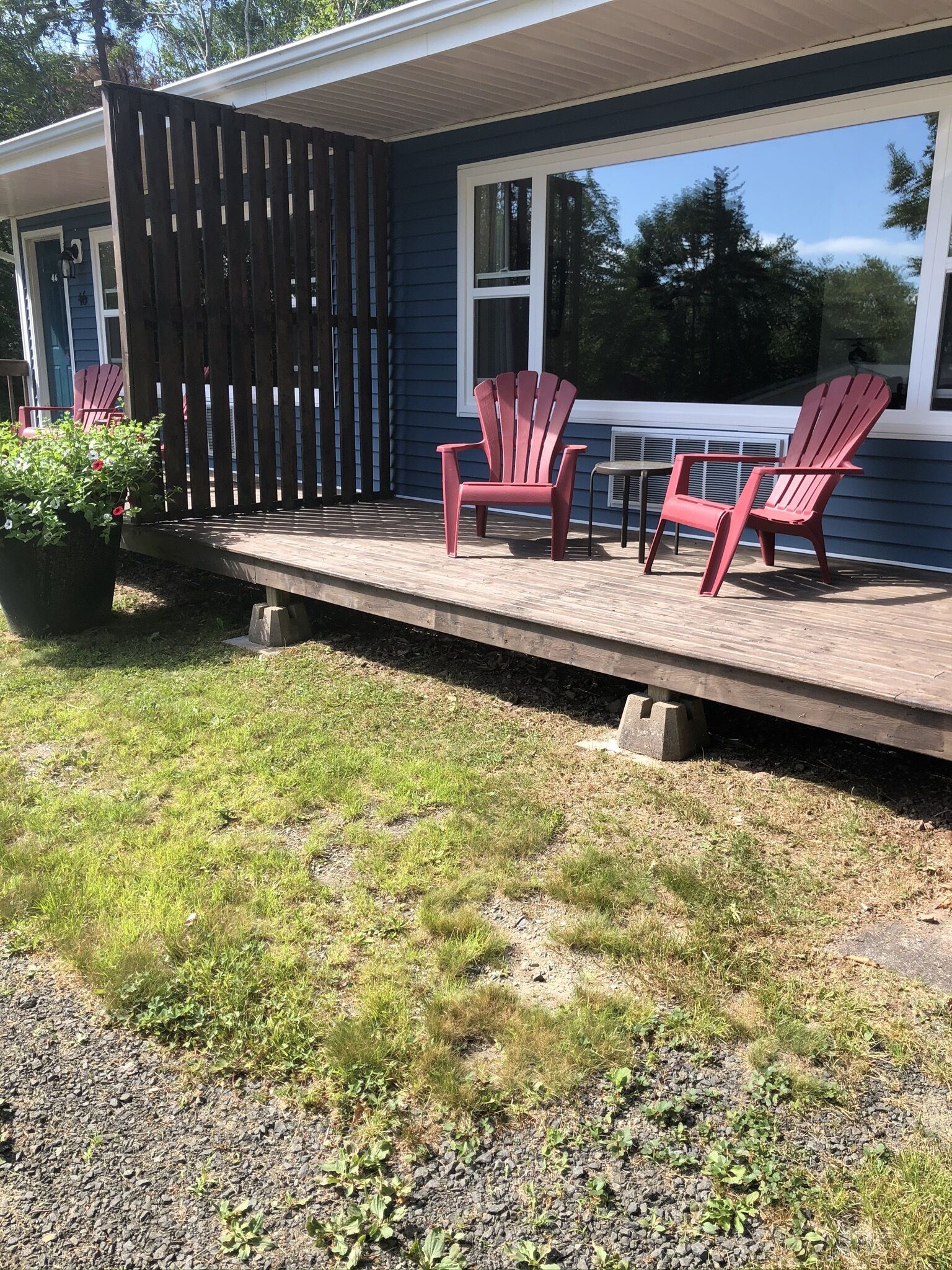 Una terraza con sillas Adirondack, una planta en maceta y una pequeña mesa.