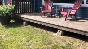Una terraza con sillas Adirondack, una planta en maceta y una pequeña mesa.