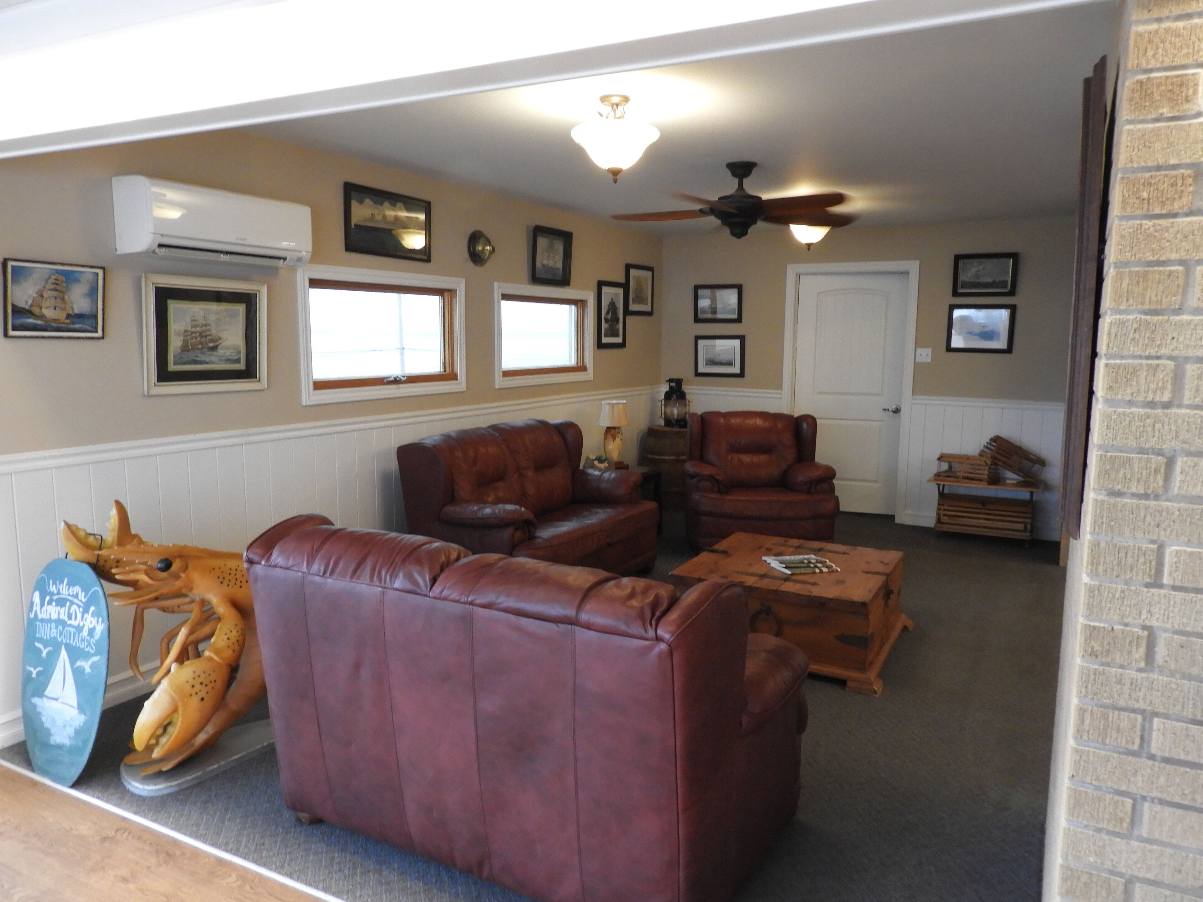 A living room with leather sofas, a wooden coffee table, and a ceiling fan.