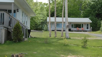 Een huis met twee verdiepingen, een veranda en een klein bijgebouw.