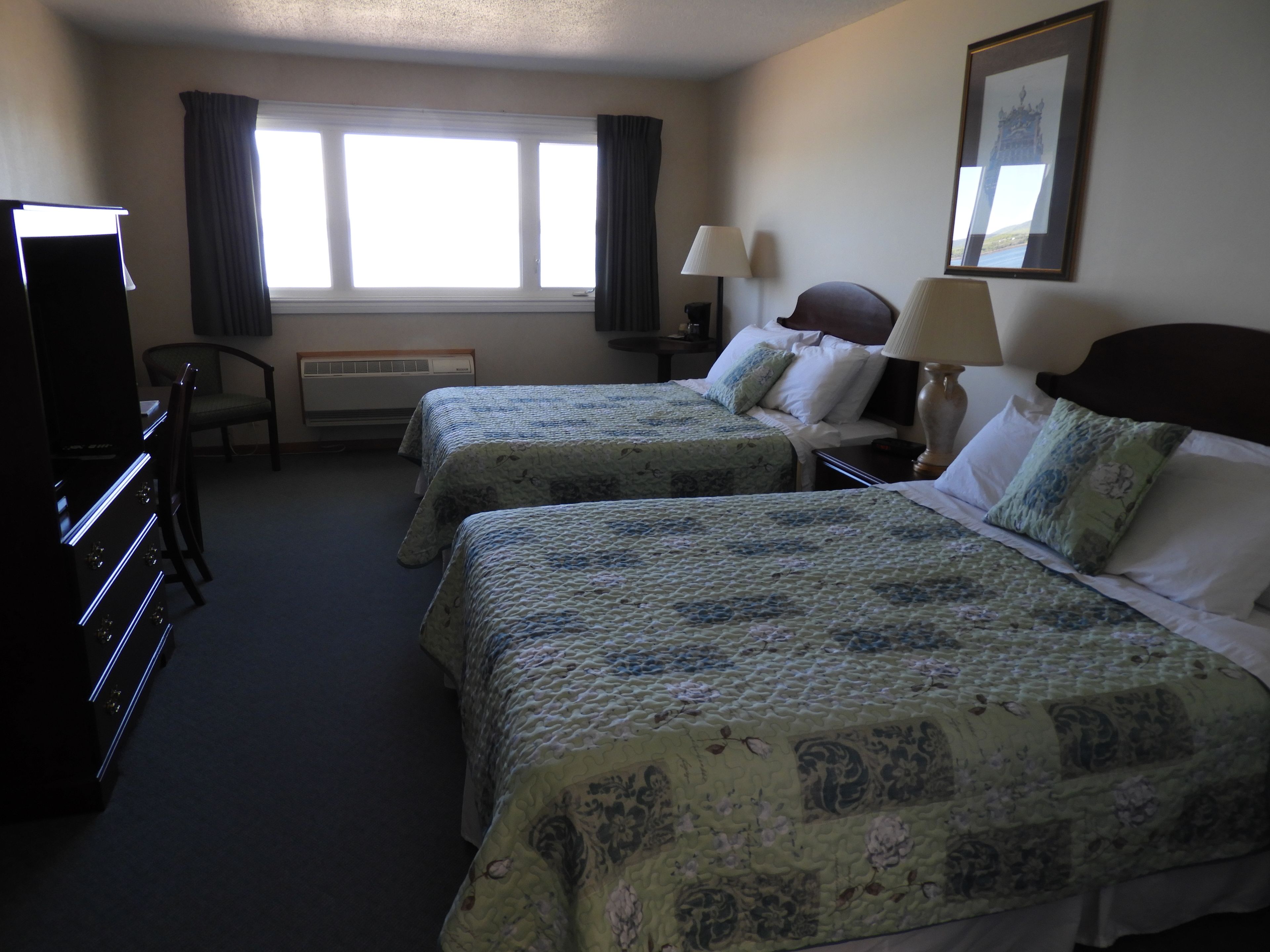 Une chambre d’hôtel avec deux lits, un bureau, une chaise et un téléviseur.