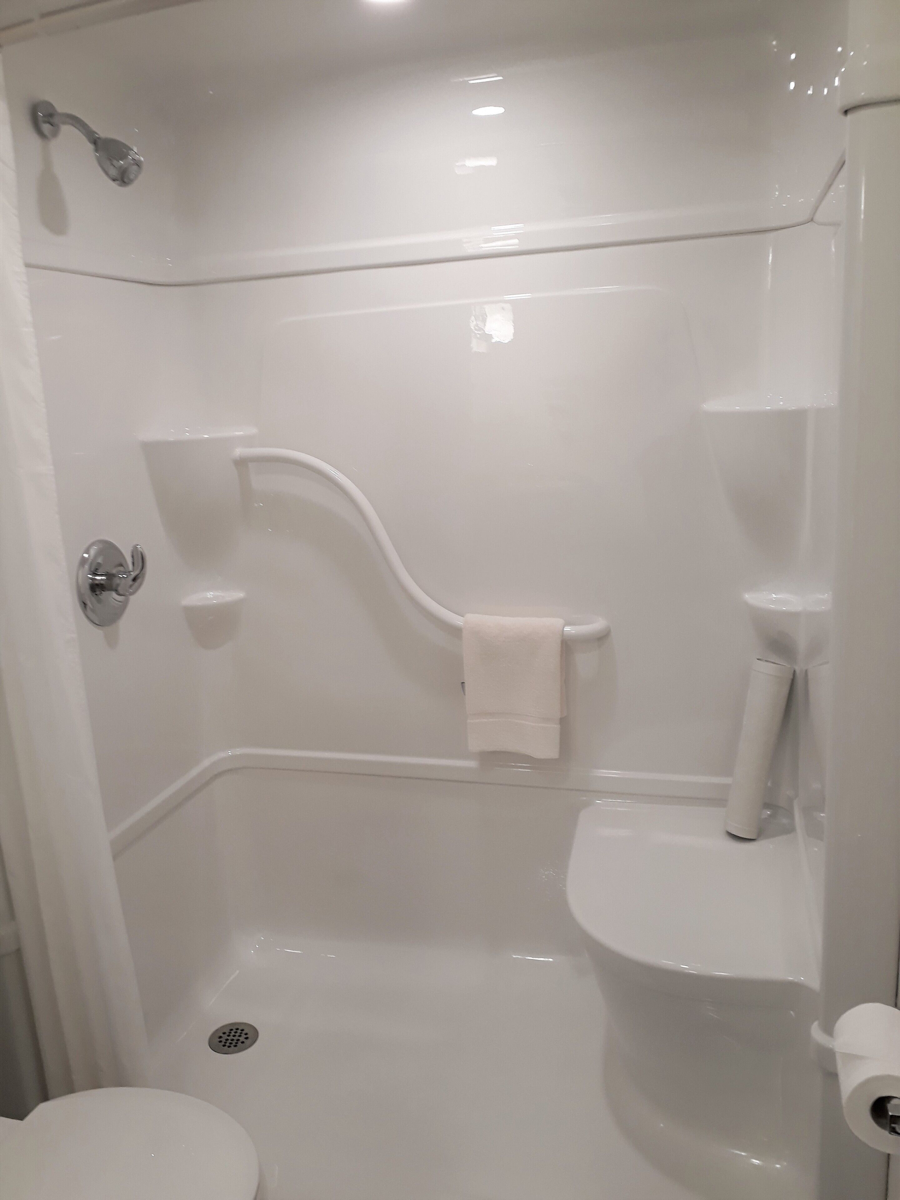 Une salle de bain blanche avec une douche, des toilettes et un porte-serviettes.