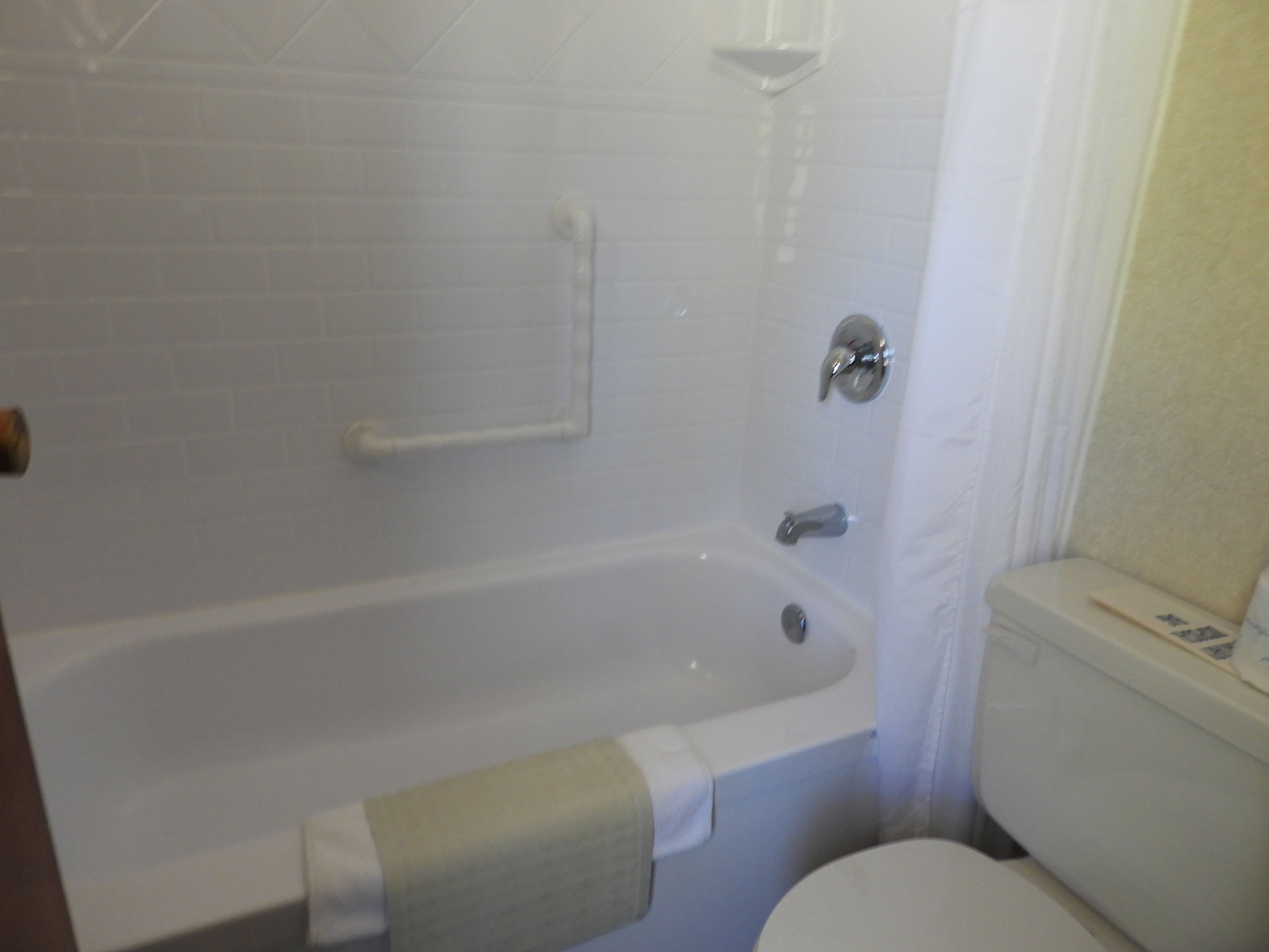 Een badkamer met een wit bad, toilet en douche.
