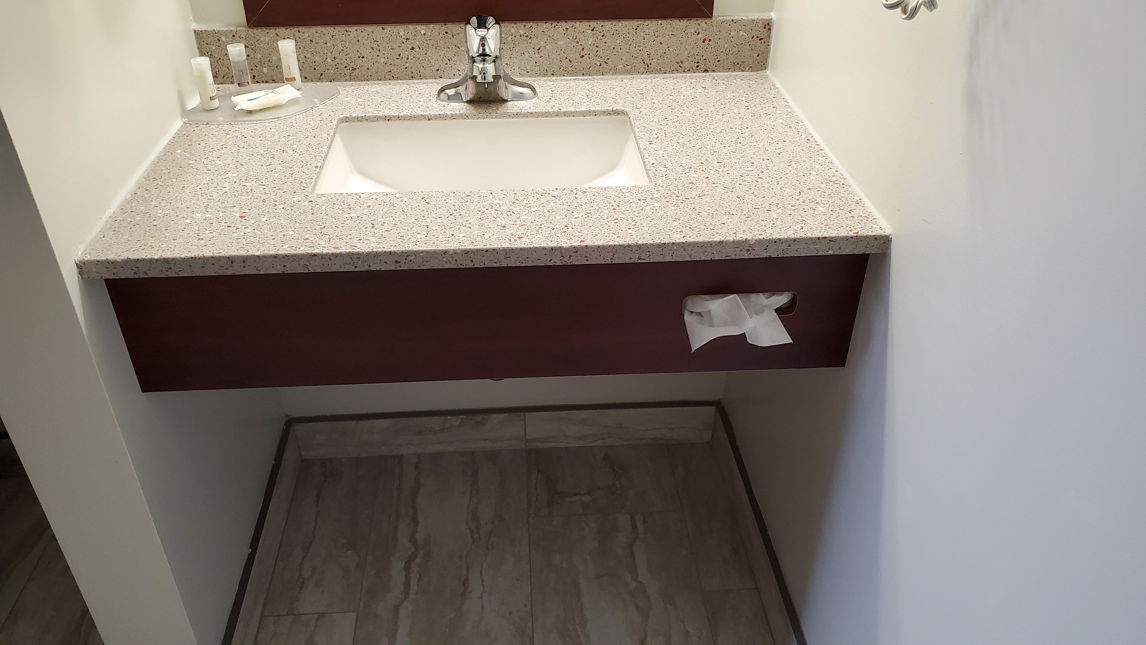 A bathroom with a sink, mirror, and a tissue box.