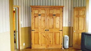 A room with a wooden wardrobe, a television, and a white appliance. - L'Intendant (Québec City)