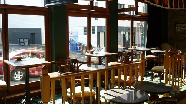 A restaurant with wooden furniture, large windows, and a view of the street outside. - L'Intendant (Québec City)