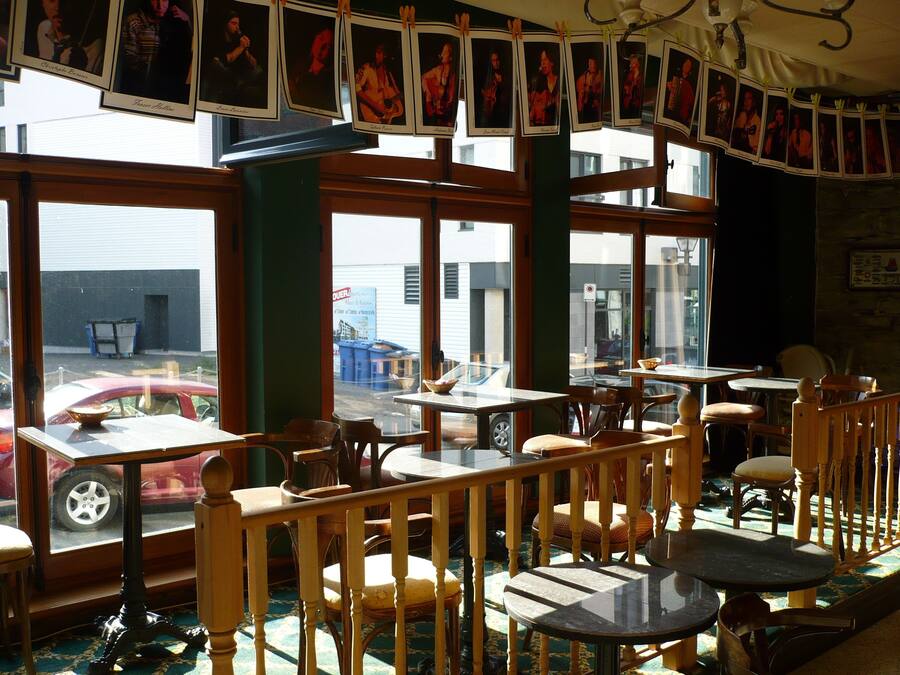 Un restaurante con mobiliario de madera, amplias ventanas y vista a la calle.