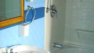 A bathroom with a sink, mirror, and shower.