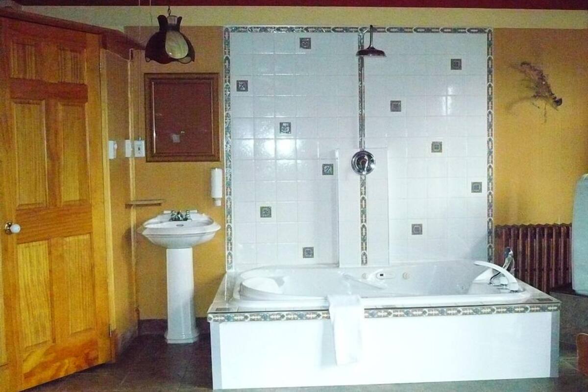 Kylpyhuone, jossa on suuri kylpyamme, pesuallas ja suihku.