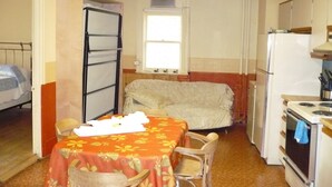 A compact room with a bed, a table with chairs, a refrigerator, and a stove. - L'Intendant (Québec City)