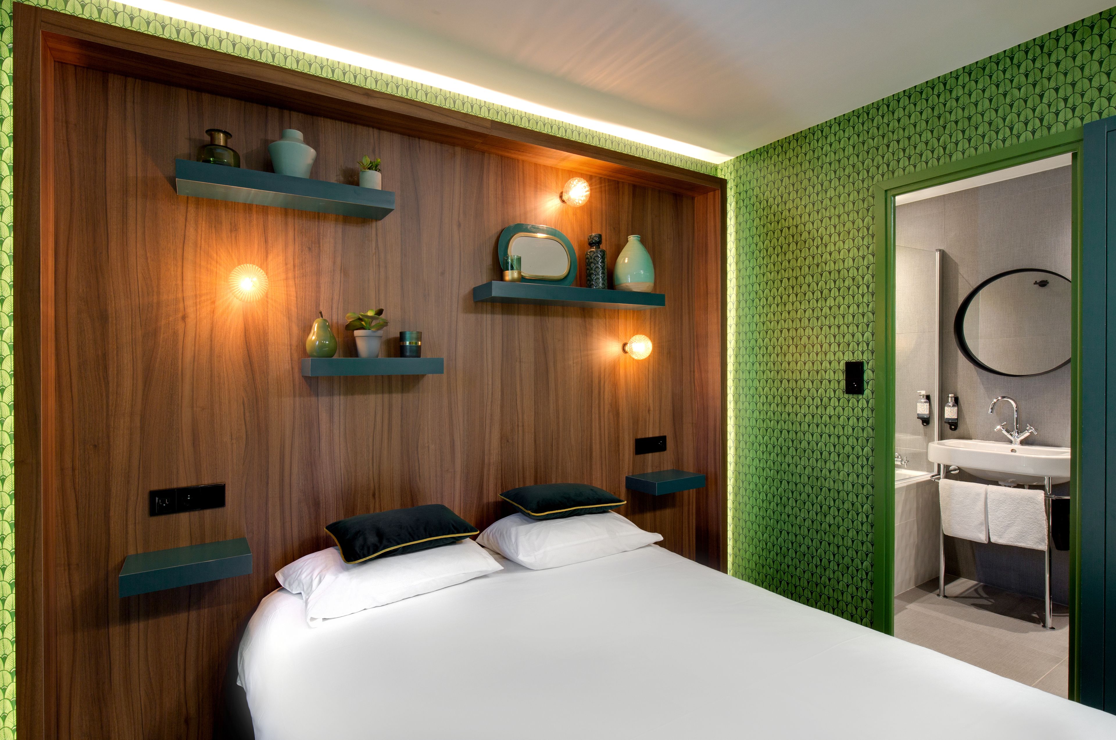 A modern bedroom with a wooden headboard, two bedside tables, and a built-in shelf with decorative items.