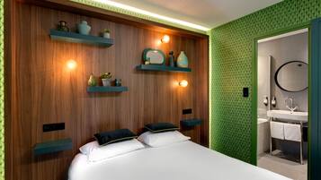 Un dormitorio moderno con cabecera de madera, dos mesitas de noche y una estantería empotrada con objetos decorativos.