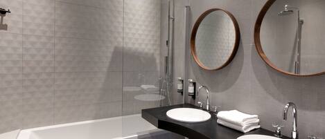 A modern bathroom with a bathtub, two sinks, and two mirrors.