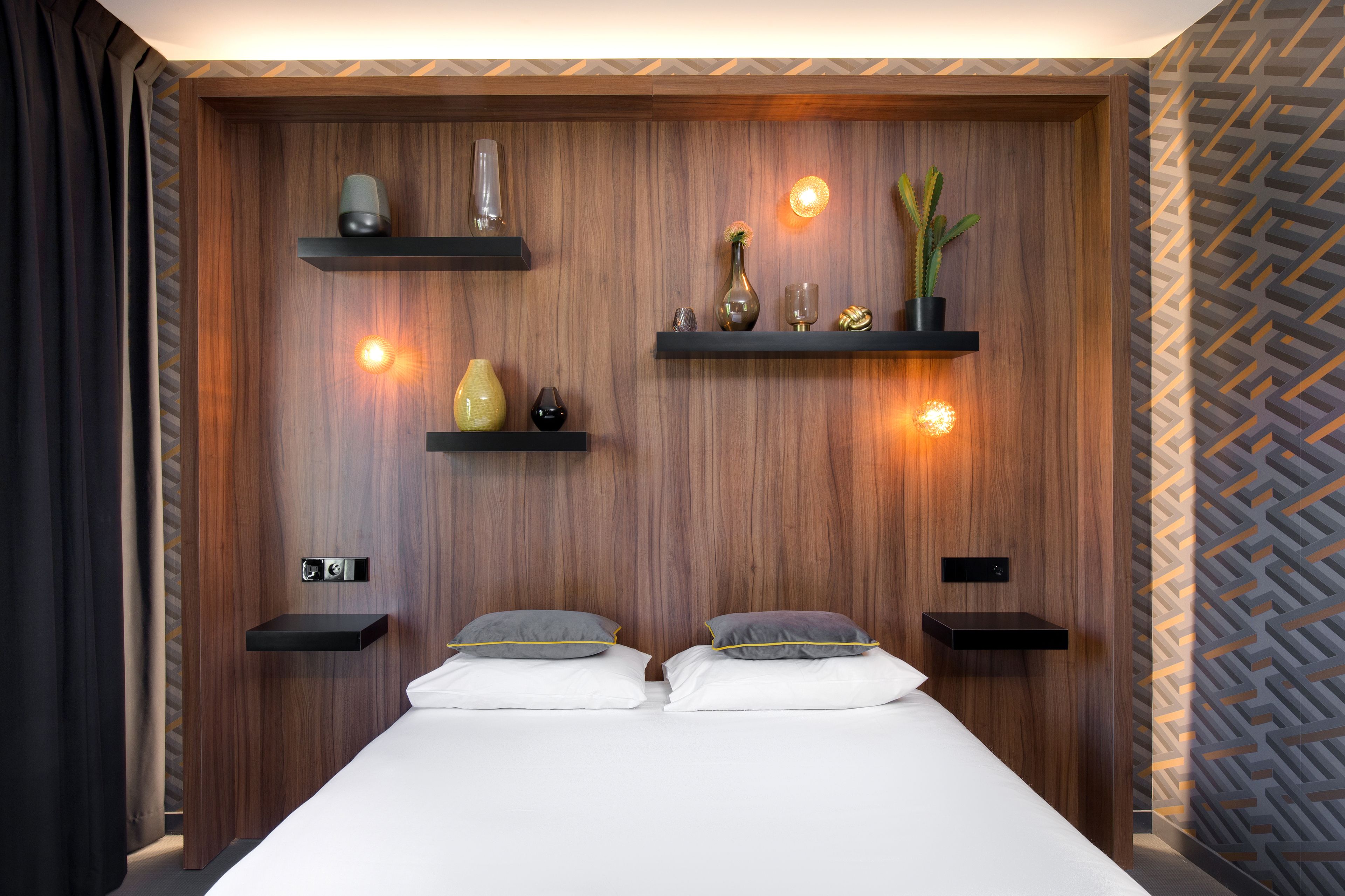 Een moderne slaapkamer met een houten hoofdbord, twee nachtkastjes en een bed met witte lakens.
