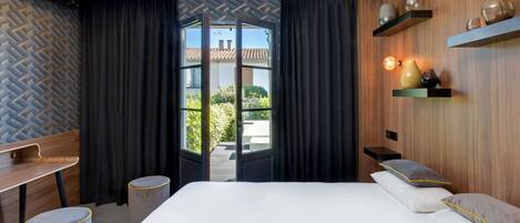 Una habitación de hotel moderna con una cama, un escritorio y vistas al exterior.