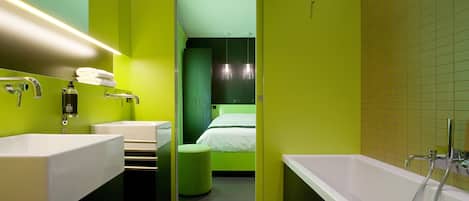 A modern bathroom with a large white bathtub, two sinks, and a green accent wall.