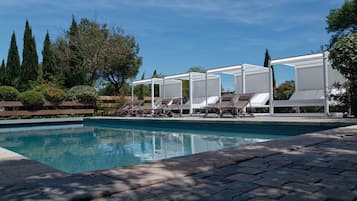 Una piscina al aire libre, sillones reclinables de piscina