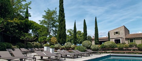 A pool area with lounge chairs and a building in the background.