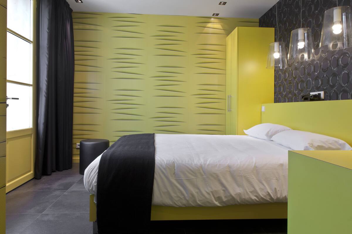 Ein modernes Schlafzimmer mit einem gelben Bett, weißer Bettwäsche und einer Wand mit Muster.