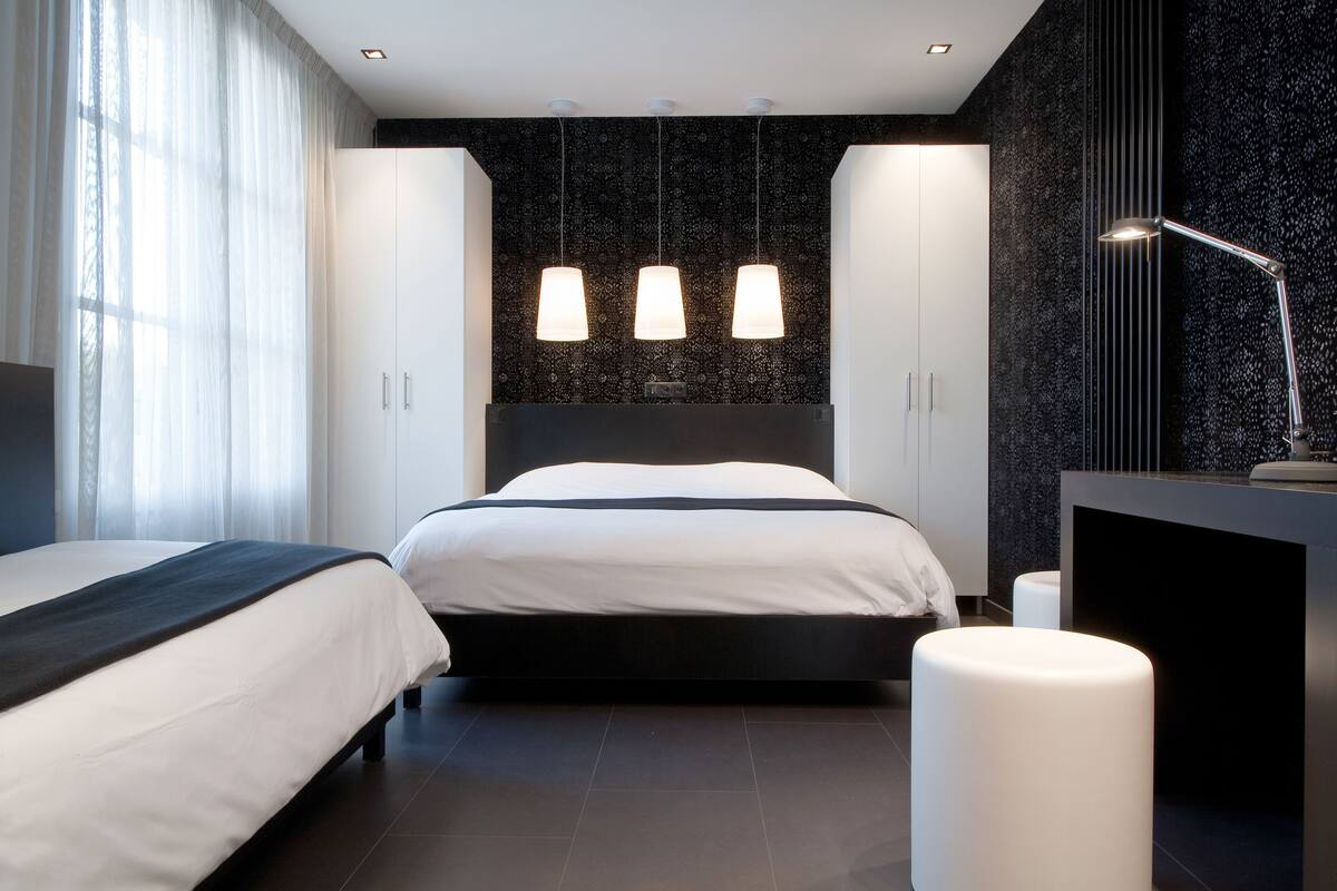 Ein modernes Hotelzimmer mit einem großen Bett, Nachttischen und einem Schreibtisch mit einer Lampe.