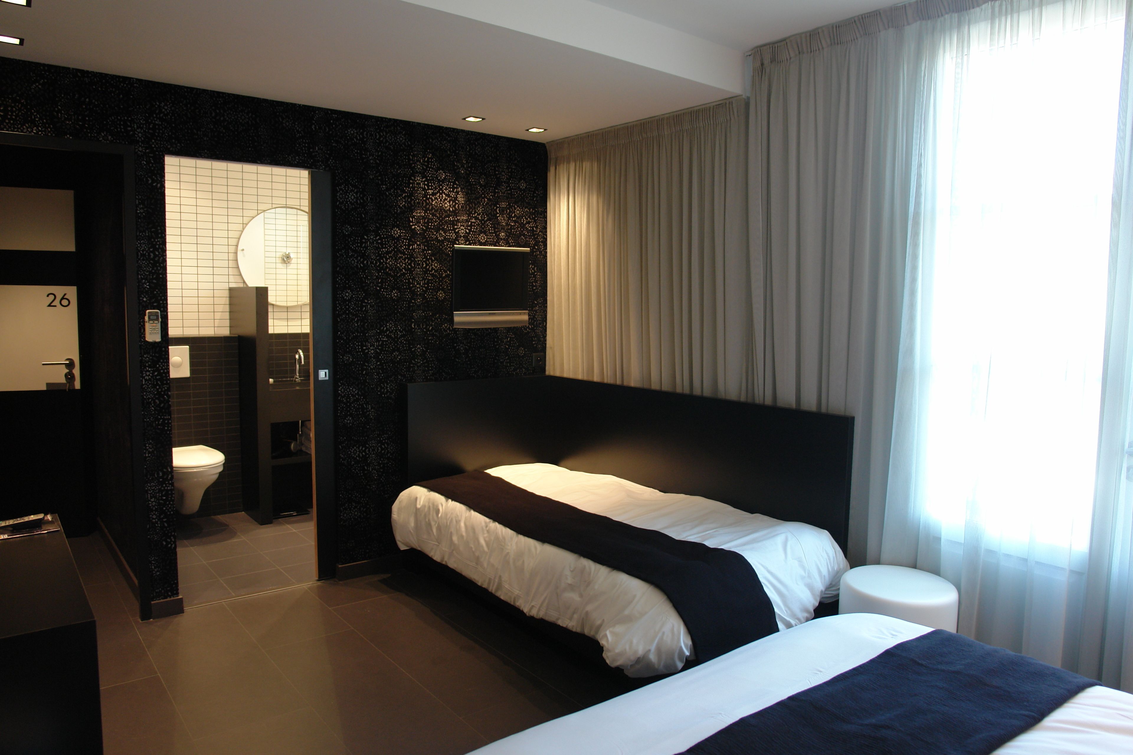 Una habitación de hotel moderna con una cama grande, baño independiente y vista a la ciudad.