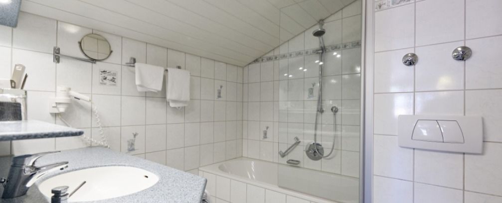 A bathroom with a sink, mirror, and shower.