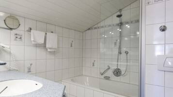 A bathroom with a sink, mirror, and shower.
