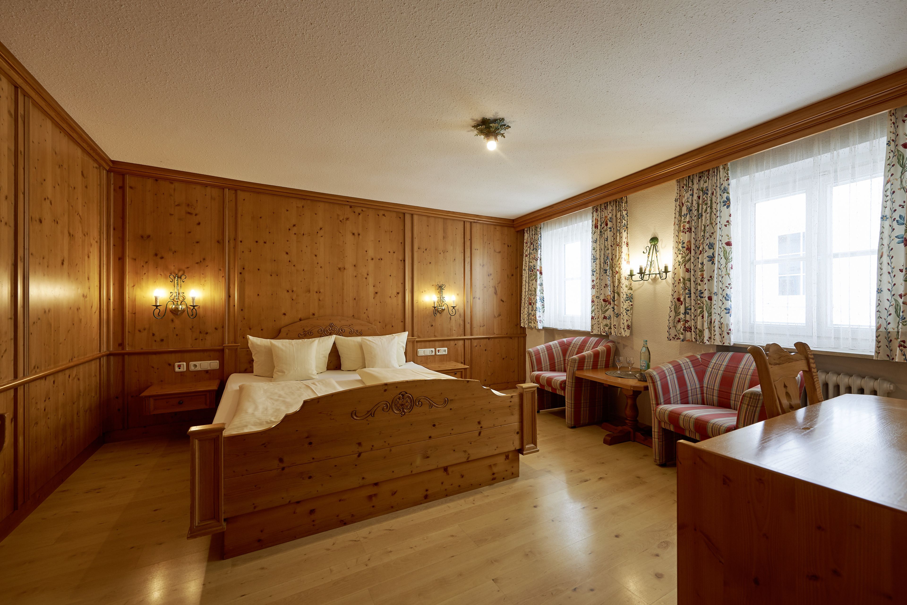 Une chambre à coucher aux murs lambrissés, avec un lit, un bureau en bois et un canapé.