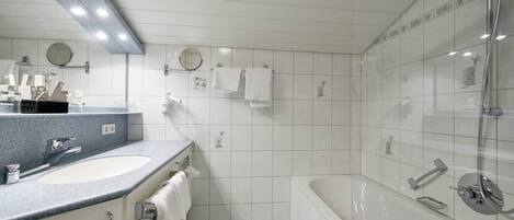 A modern bathroom with two sinks, a bathtub, and a shower.
