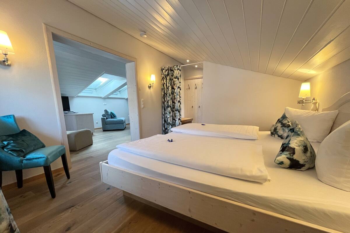A modern bedroom with a large bed, a sofa, and a desk.