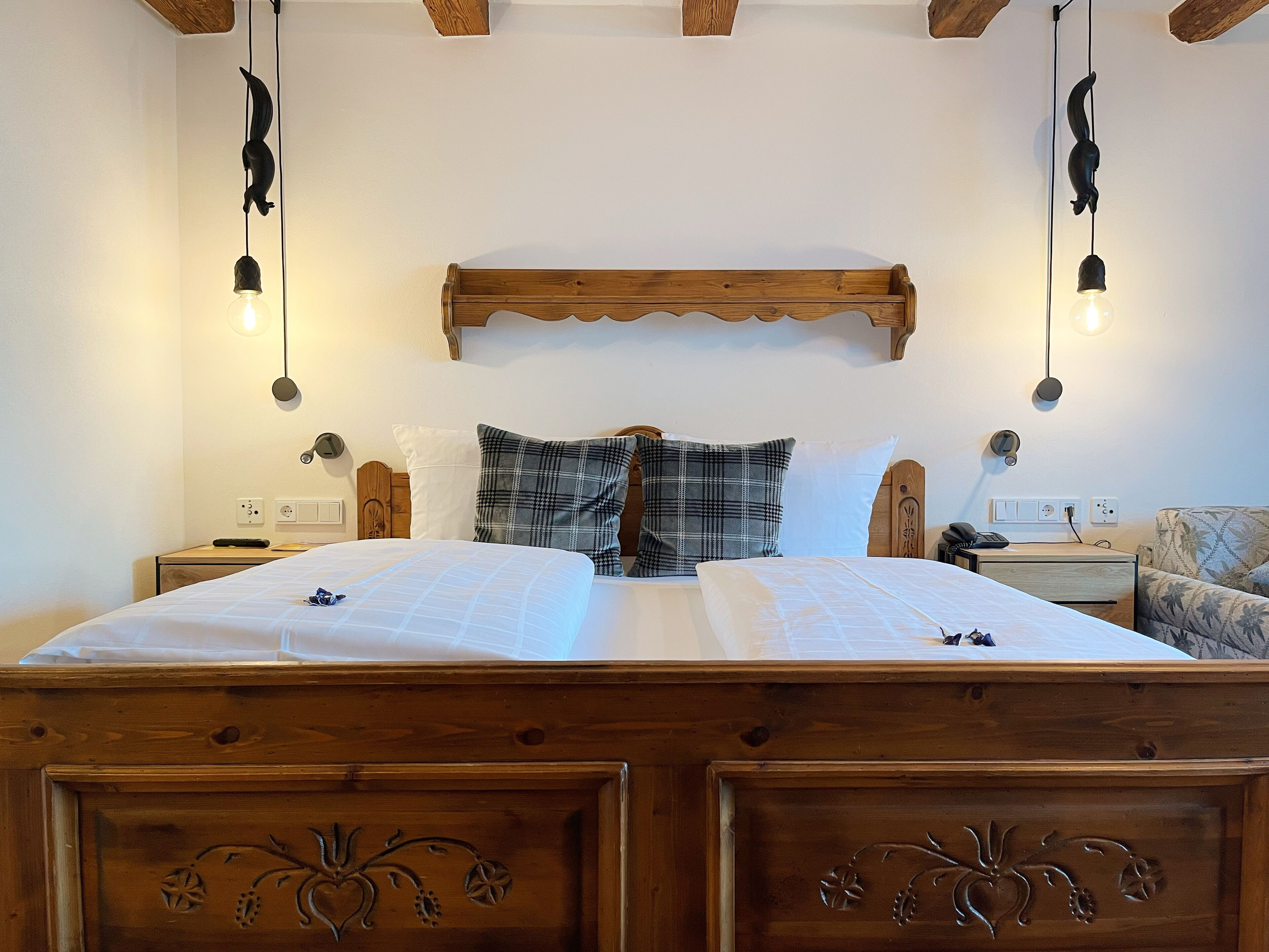 Ein Doppelbett mit Holz-Kopfteil, zwei Nachttische, ein Beistelltisch, ein Sessel und Pendelleuchten.