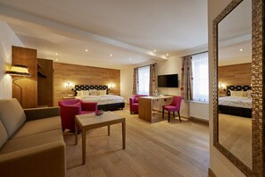 Una habitación de hotel moderna con sofá, dos camas, escritorio y televisor.