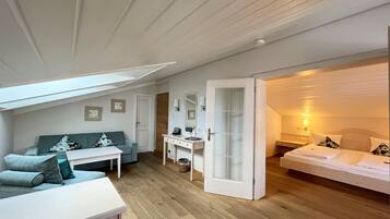 A compact room with a sofa, a desk, a bed, and a small bathroom.