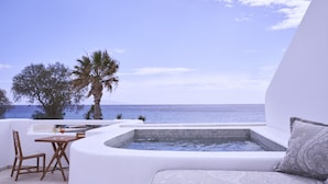 A private balcony with a hot tub, seating area, and a view of the sea. - Makris Beach Hotel (Santorini)