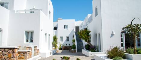 A narrow street with white buildings, stone steps, and potted plants.