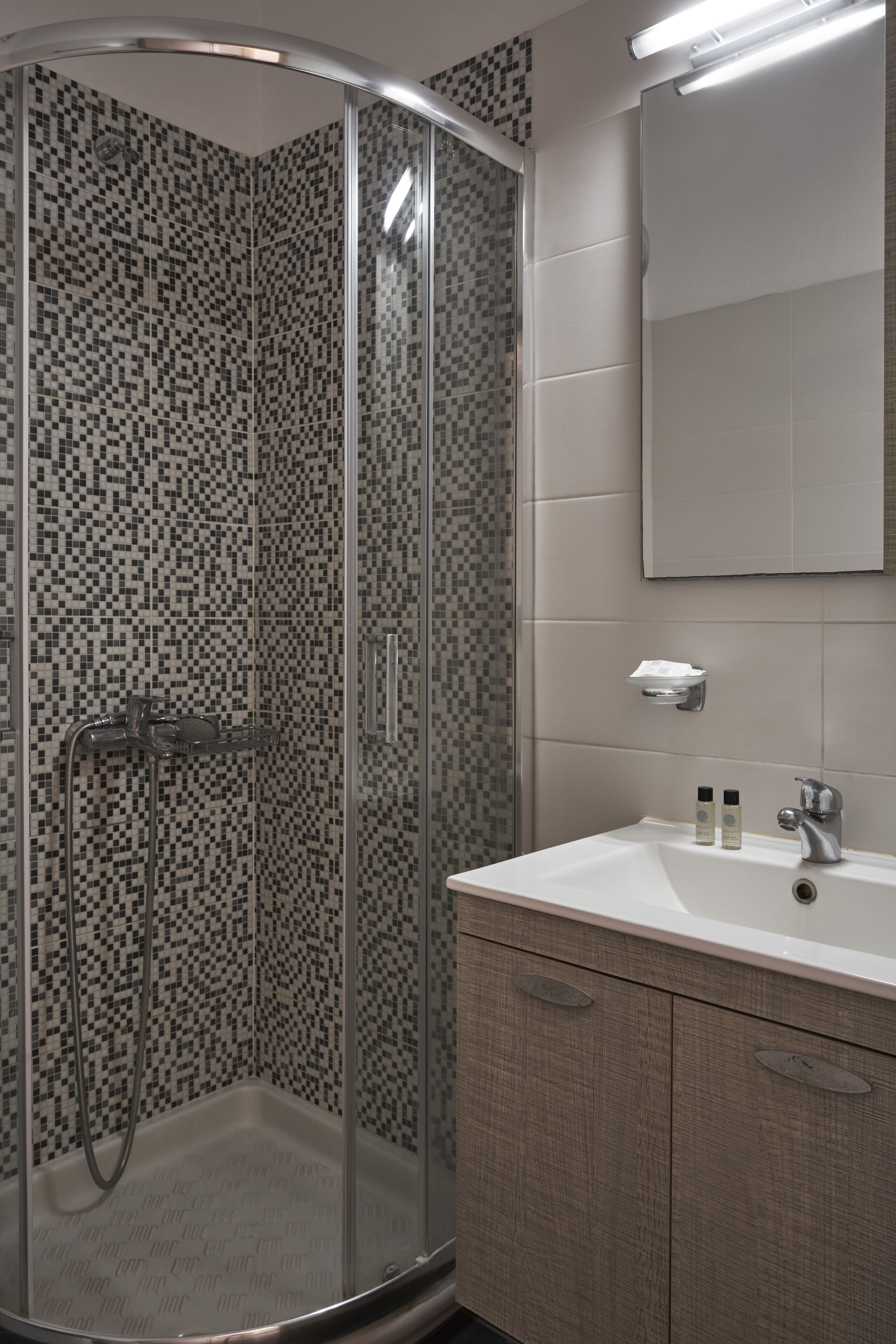A modern bathroom with a glass-enclosed shower, a white sink, and a mirror above it.
