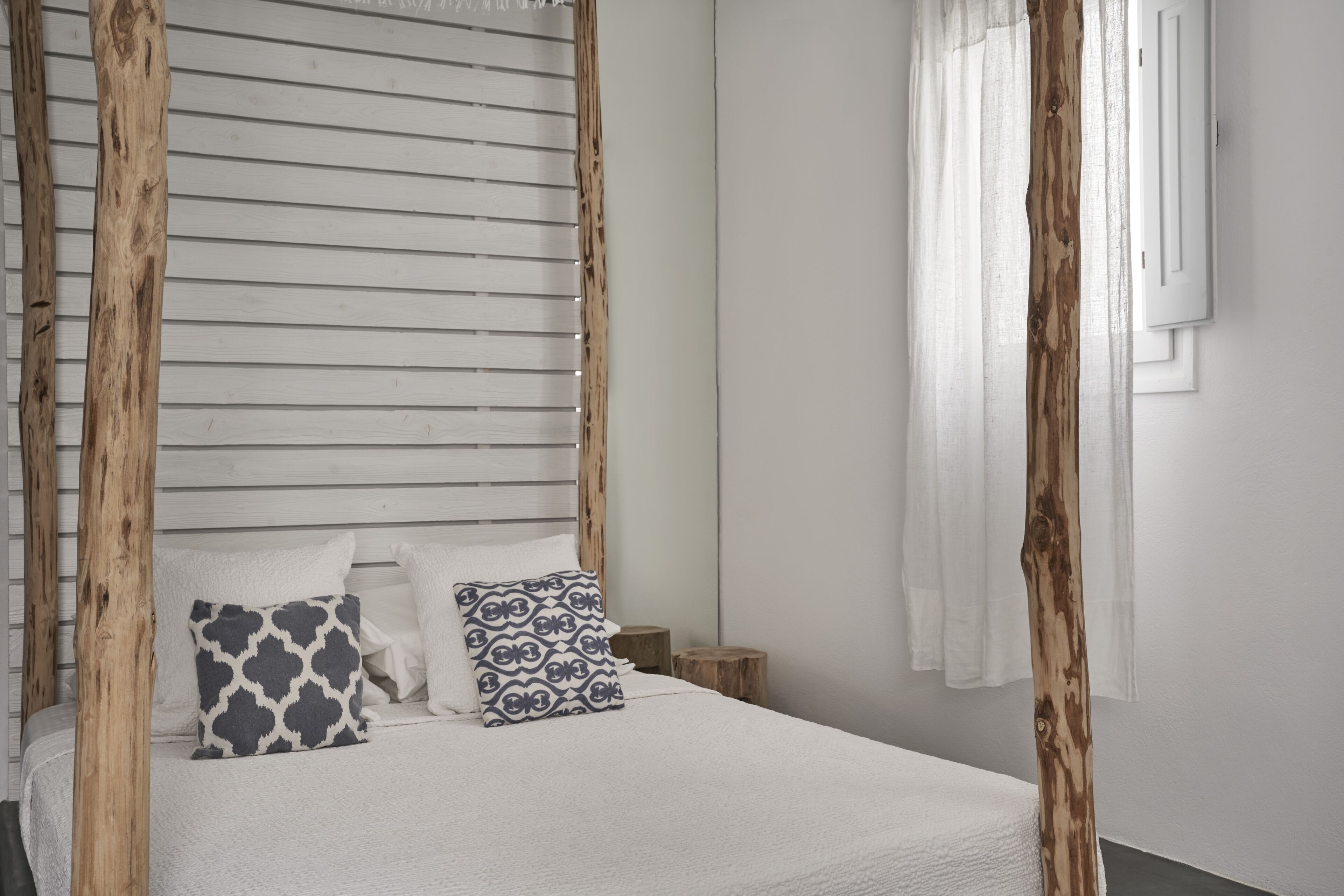 Ein Schlafzimmer mit Baldachinbett, weißer Bettwäsche und zwei gemusterten Kissen.