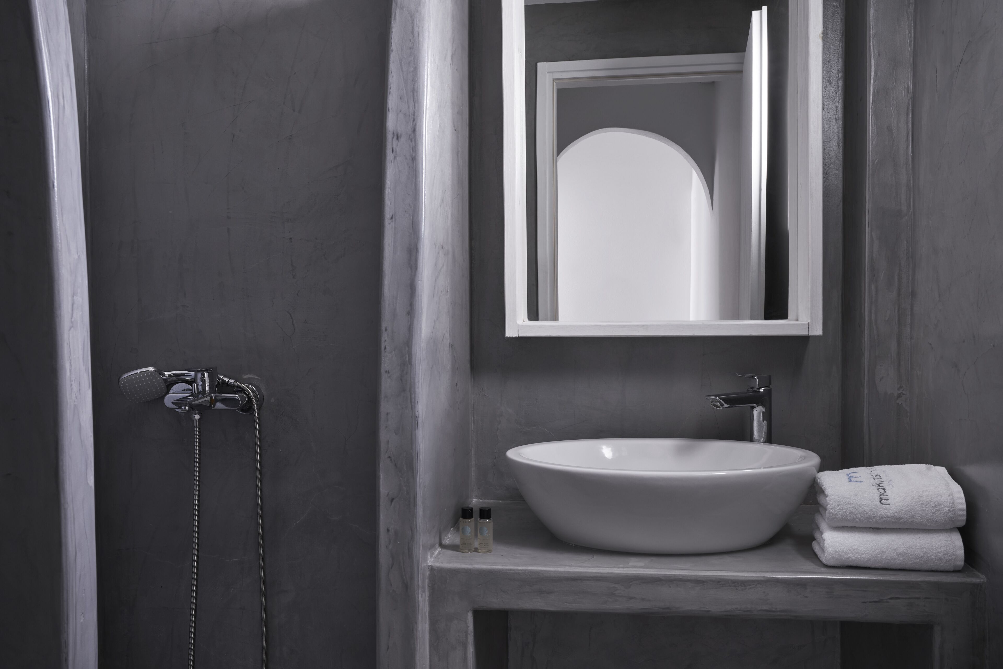 A bathroom with a large white sink, a mirror above it, and a towel rack with towels.