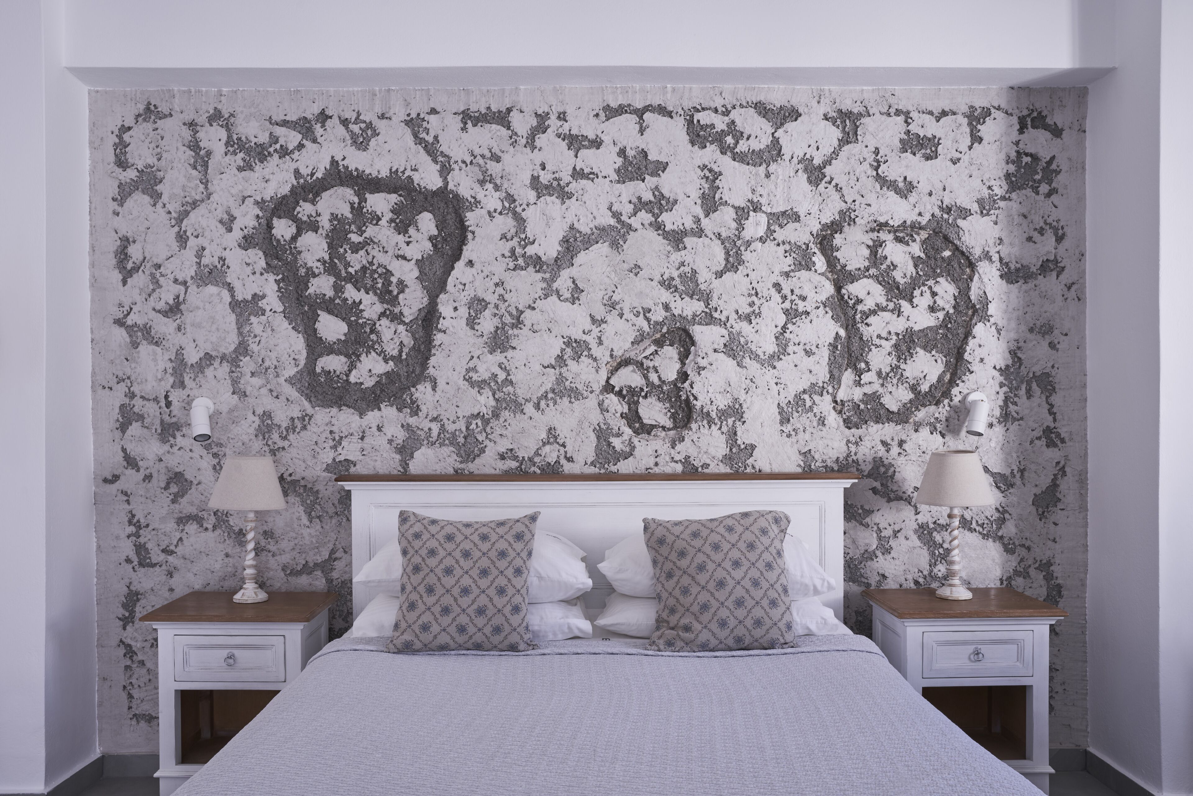 Ein Schlafzimmer mit einem Bett, zwei Nachttischen und einer strukturierten Wand.