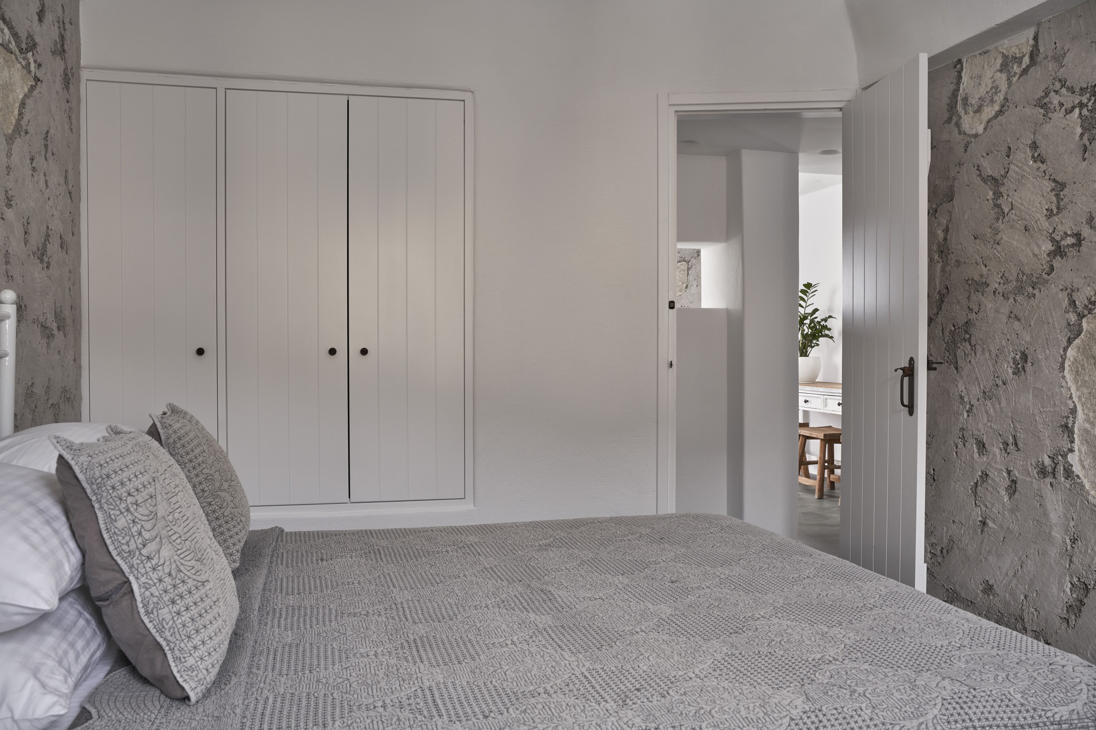 Une chambre à coucher comprenant un lit, une armoire et une porte donnant sur une autre pièce.