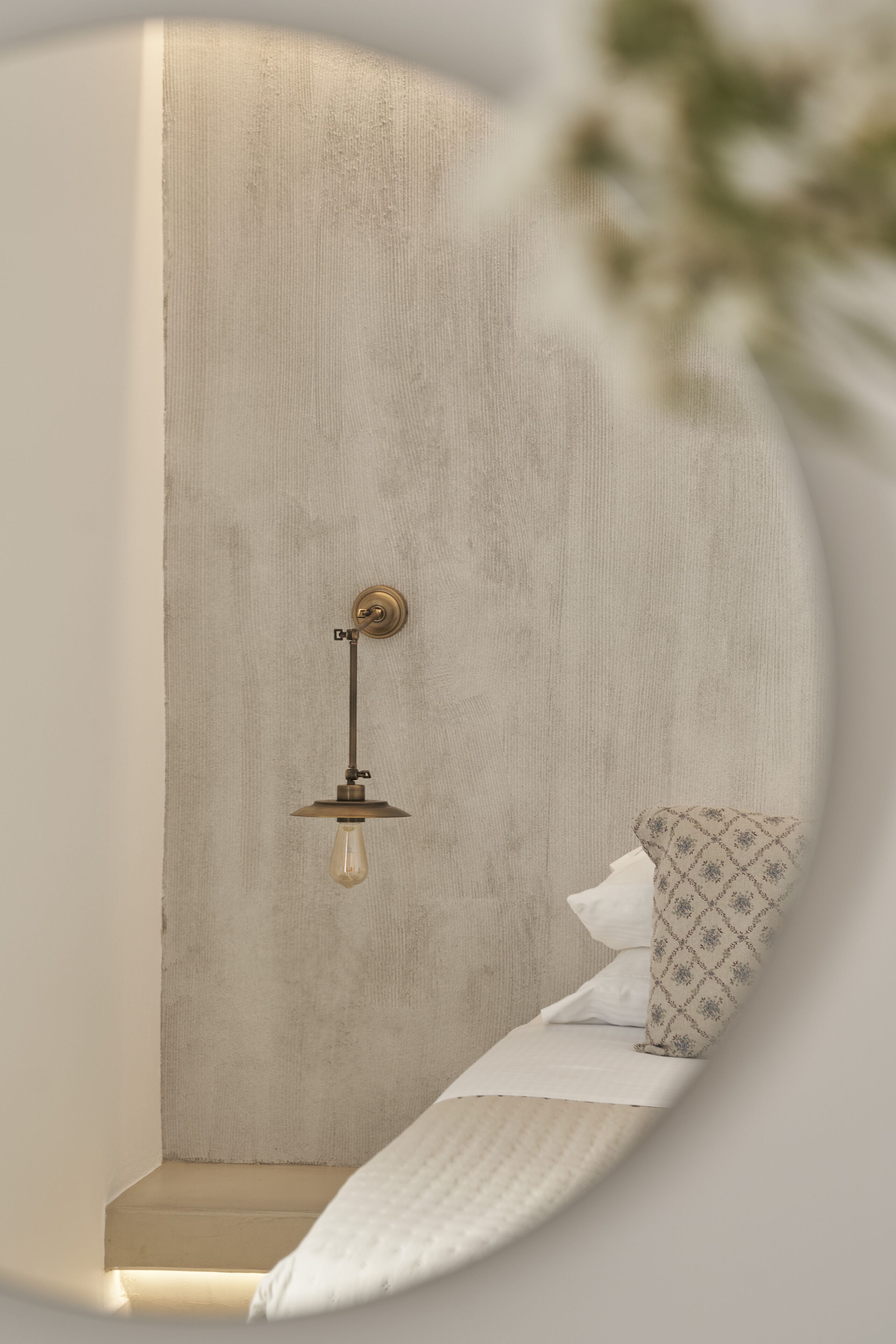 Un dormitorio con una cama individual, una mesita de noche y una lámpara fijada a la pared.
