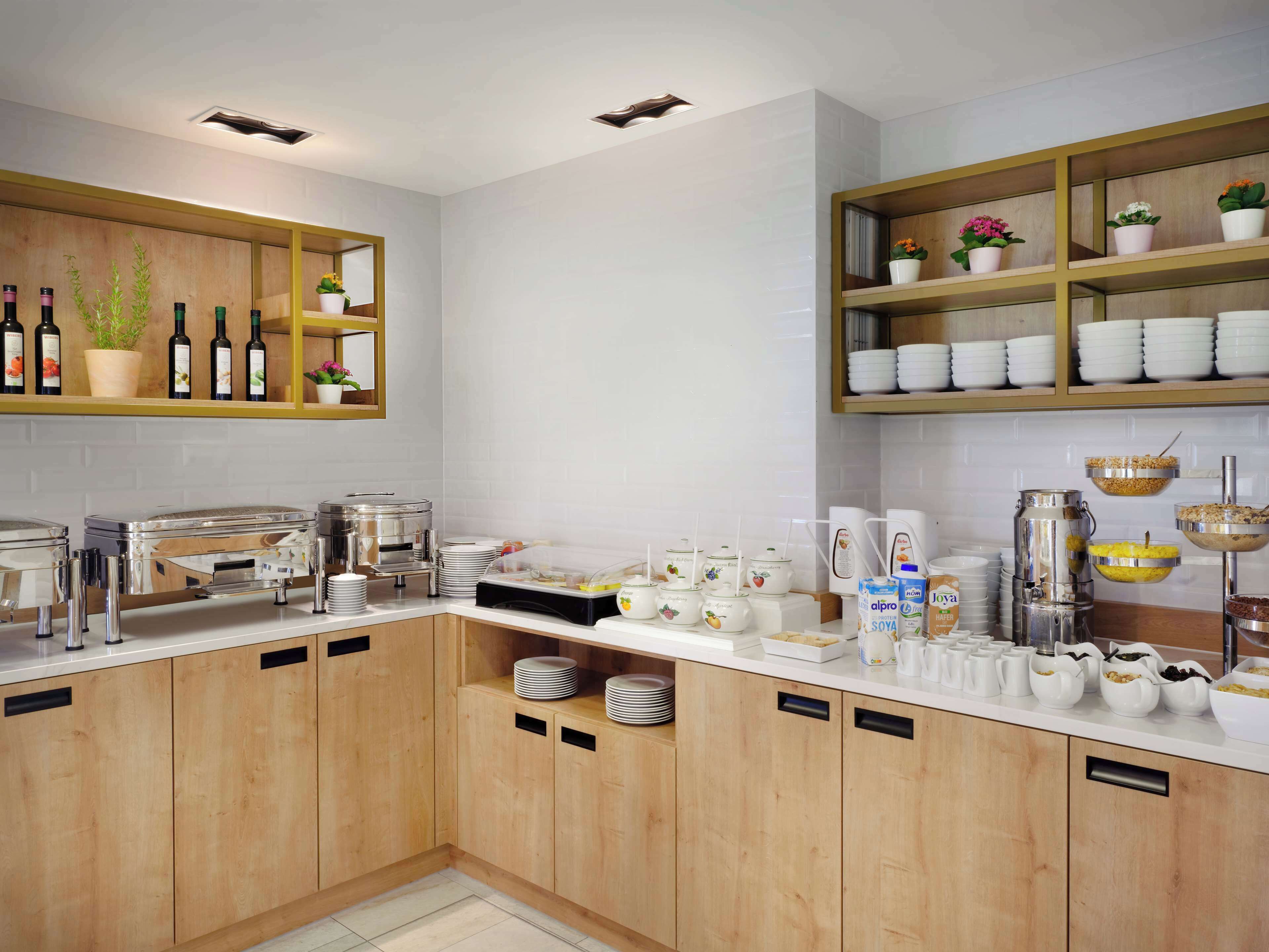 Una cocina moderna con armarios de madera, una vinoteca integrada y diversos alimentos para el desayuno sobre la encimera.