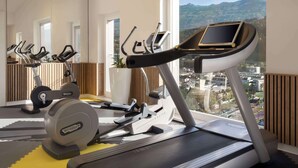 Een sportschool met loopbanden, een hometrainer en een roeimachine.