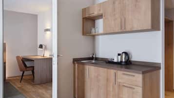 Une cuisine moderne avec des meubles en bois, un plan de travail et une bouilloire.
