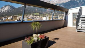 Een modern terras op het dak met uitzicht op een bergketen en een stad daaronder.